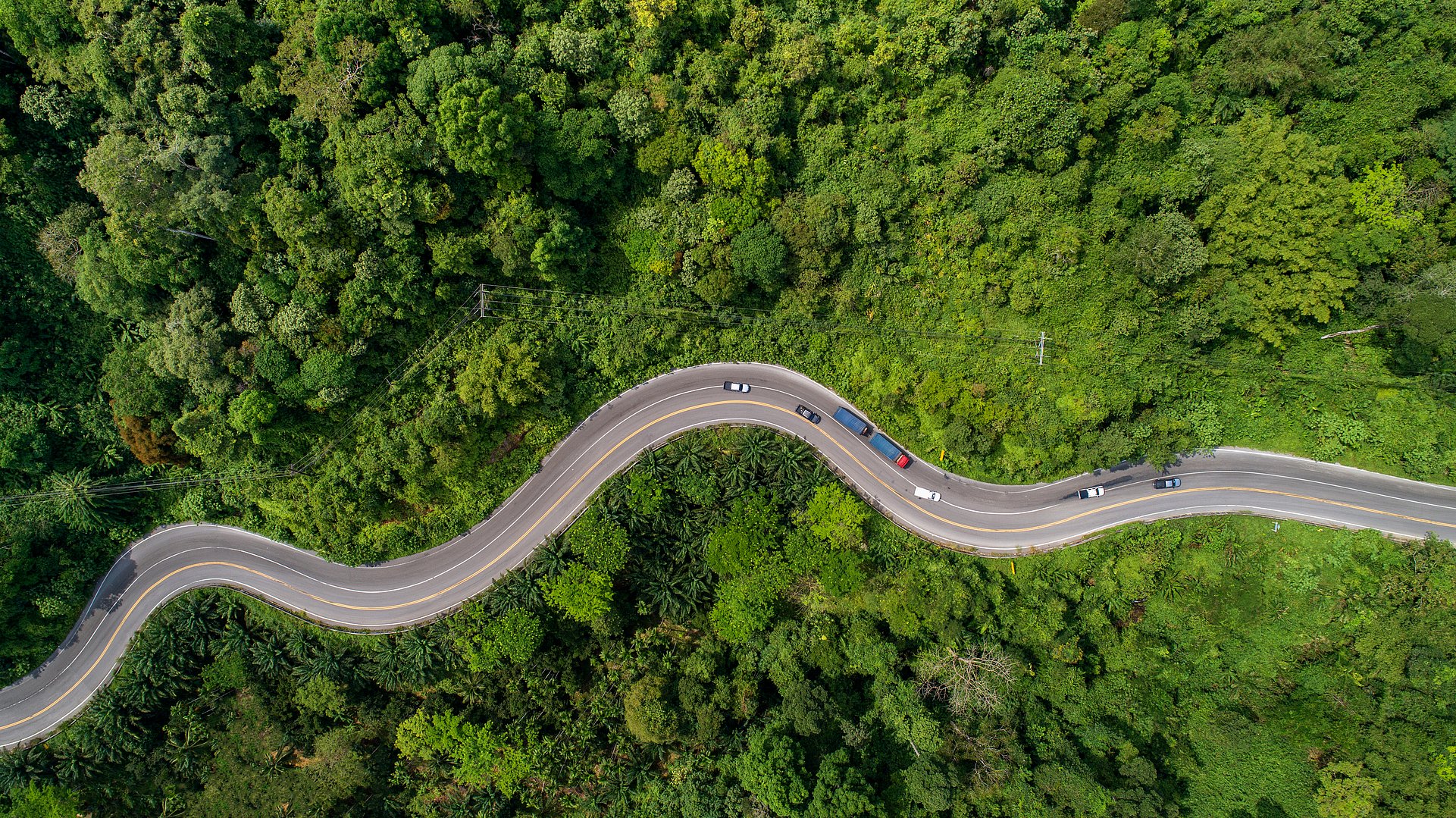 aerial view road curve construction up to mountain aerial view road curving through greenery up to mountain with cars
