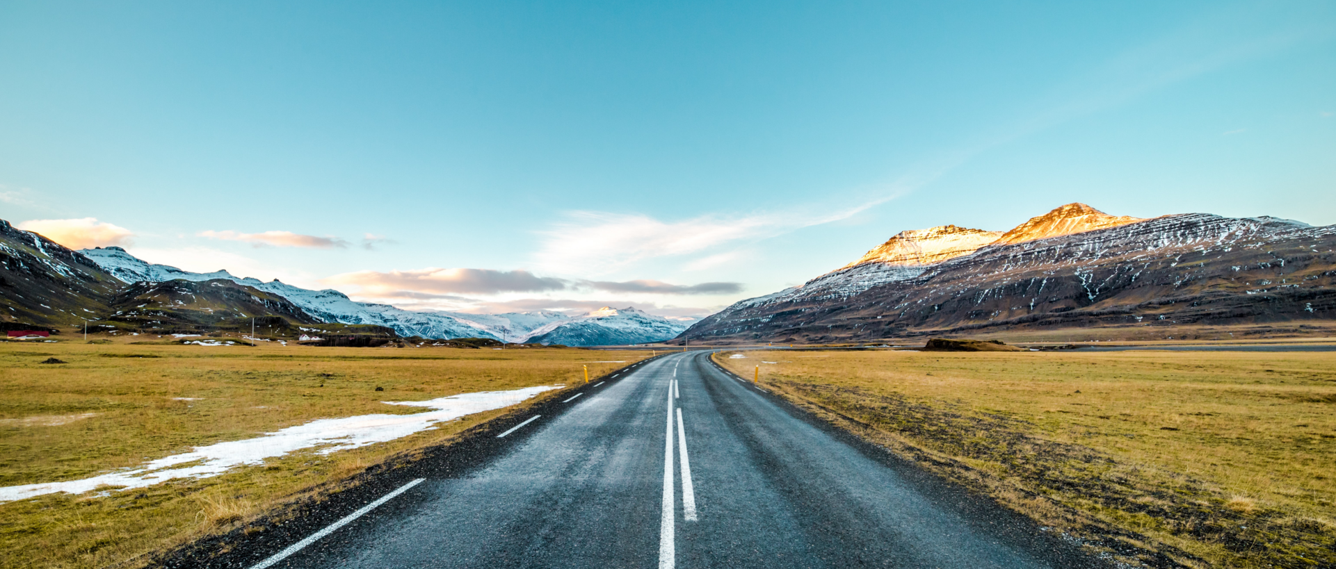 Road through field with mountains in the background