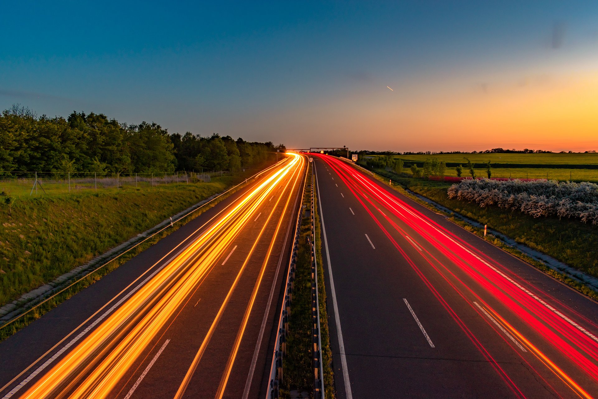 Road through countryside at sunset with streaks of light from headlights Road through countryside at sunset with streaks of light from headlights